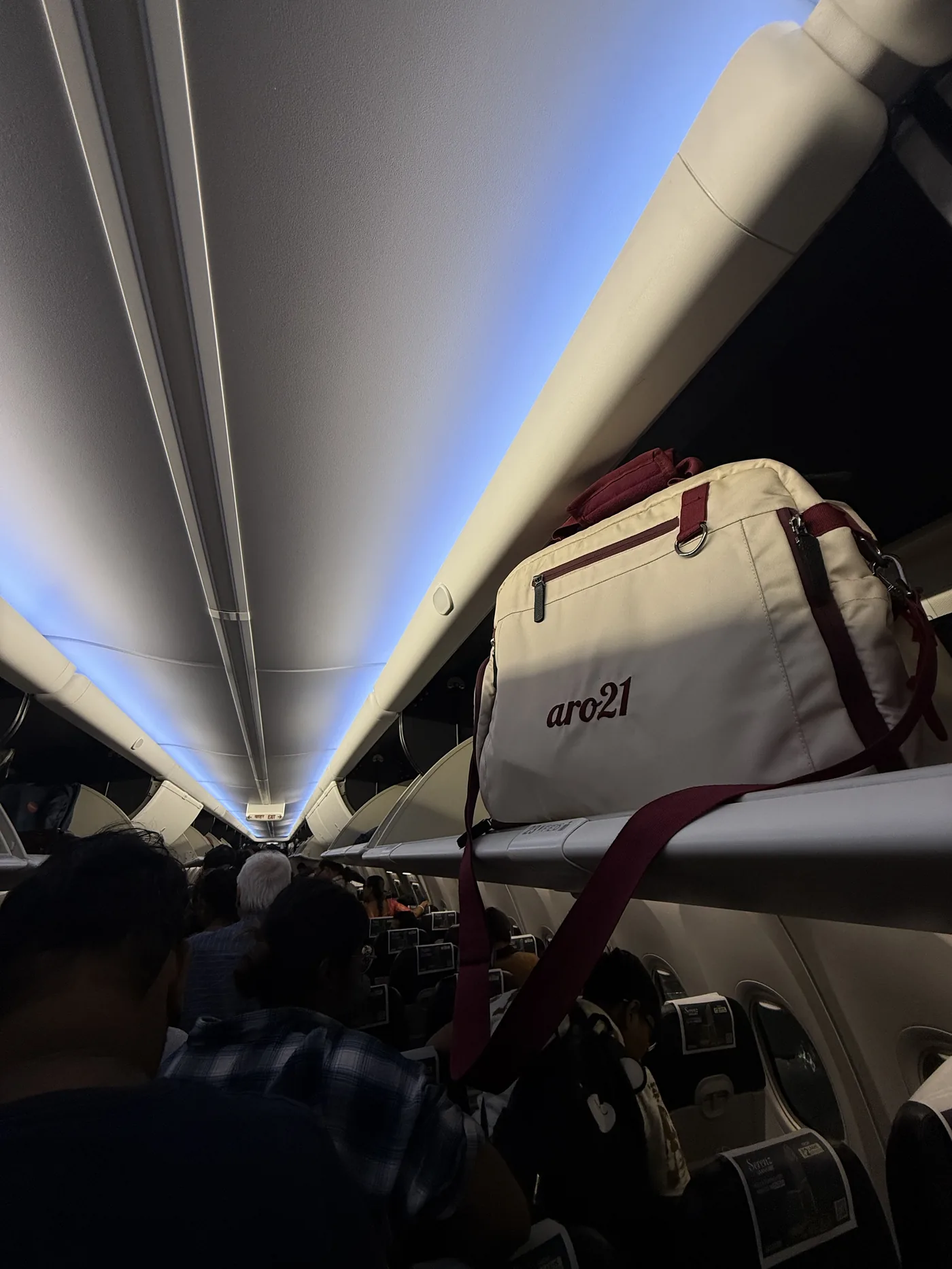 The Dawn Duffel stowed in an aircraft overhead locker, cabin lights low